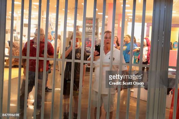 Shopppers watch from insde a locked store as demonstrators march through the West County Mall protesting the acquittal of former St. Louis police...