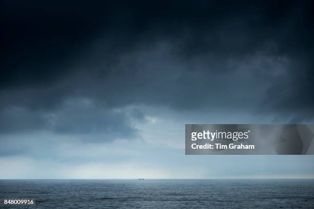 Tanker under dark looming grey storm clouds in The Bay of Biscay north of Santander in the Atlantic Ocean, Spain.