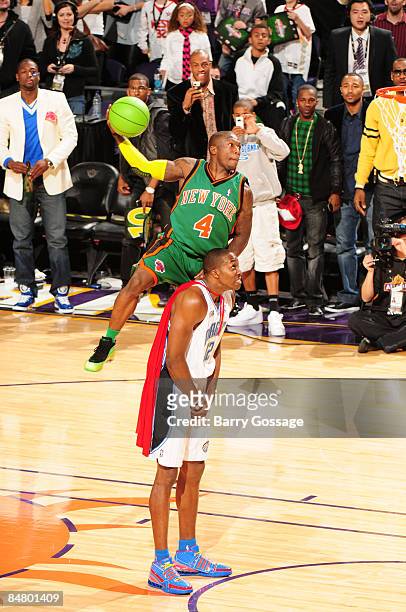 Nate Robinson of the New York Knicks attempts a dunk by jumping over Dwight Howard of the Orlando Magic during the Sprite Slam Dunk Contest as part...