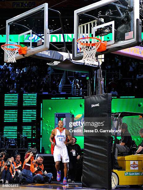 Dwight Howard of the Orlando Magic runs out of a phone booth on to the court wearing a Superman cape as he gets set to attempt a dunk on a 12-foot...
