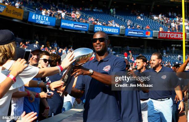Former New York Giant Plaxico Burress shares the Vince Lombardi trophy with fans prior to a game between the New York Yankees and the Baltimore...