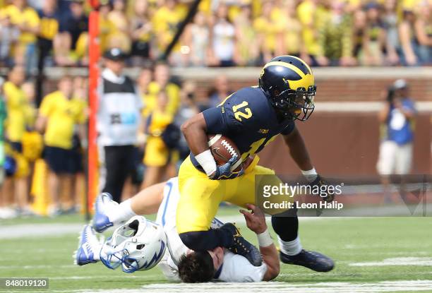 Chris Evans of the Michigan Wolverines runs for a first down as Jack Flor of the Air Force Falcons makes the stop and loses his helmet during the...