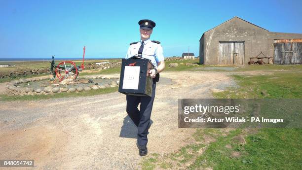 Garda Eugene Organ carrying a ballot box to the polling station for voting on the fiscal treaty referendum on Tory Island off the coast of Donegal,...