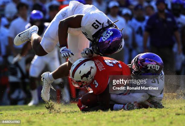 James Proche of the Southern Methodist Mustangs is tackled by Montrel Wilson and Ridwan Issahaku of the TCU Horned Frogs in the second half at Amon...
