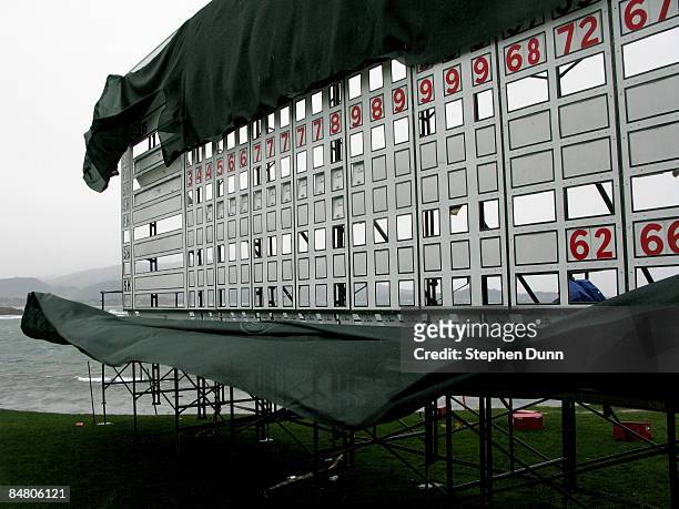 Draping on the scoreboard at the 18th green blows in strong winds during a weather delay before the final round of the AT&T Pebble Beach National...