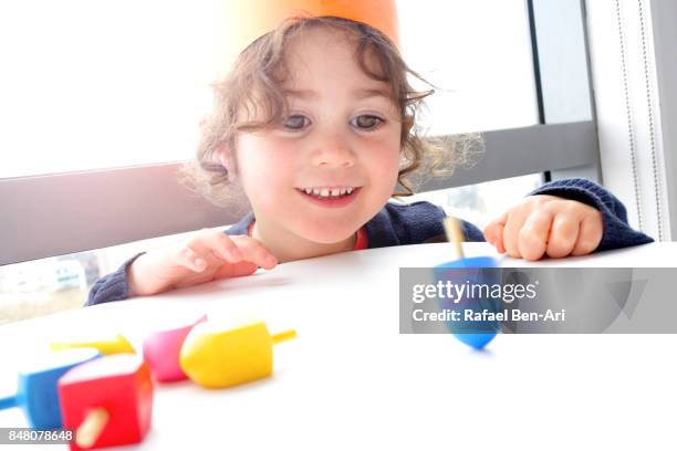 little girl plays with dreidels on hanukkah jewish holiday - ドライデル ストックフォトと画像