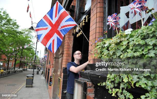 Dan Williams puts up a union flag at during preparations for a Jubilee street party on Canal Street in Manchester.