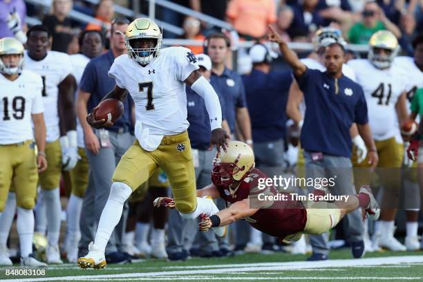 Brandon Wimbush of the Notre Dame Fighting Irish rushes for 46-yards as Kevin Bletzer of the Boston College Eagles attempts to tackle him during the...