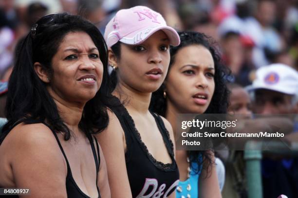 Three Cuban women watch a training match of Cuba's National Baseball team, separated with an East and West Cuba team, at the Estadio Latinoamericano...