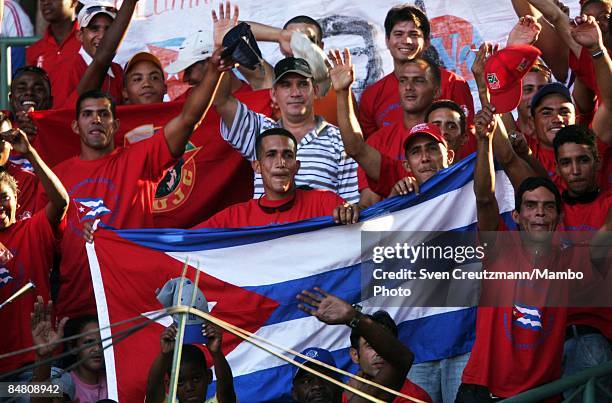 Cuban baseball fans hold up the Cuban national flag as they cheer during a training match of Cuba's National Baseball team, separated with an East...