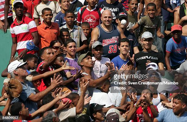 Cuban baseball fans reach out to catch a home-run ball during a training match of Cuba's National Baseball team, separated with an East and West Cuba...