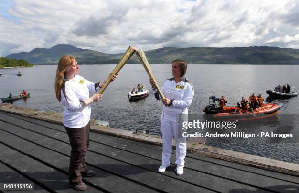Olympic torchbearer Ruth Leith hands over the Olympic flame to Sheila McNeil in the village of Luss, on the banks of with Loch Lomond.