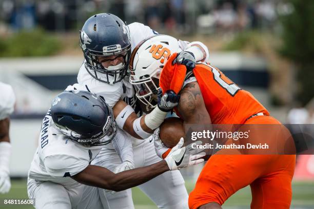 Running back Ty Flanagan of the Idaho State Bengals is stopped by defensive back Jaden Sawyer of the Nevada Wolf Pack and defensive back EJ Muhammad...