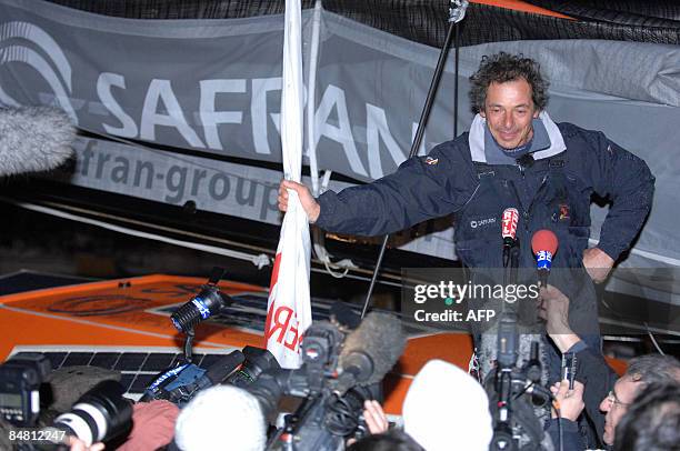 French skipper Marc Guillemot celebrates after crossing the finish line of the round-the-world solo sailing race on February 16 in the western-French...