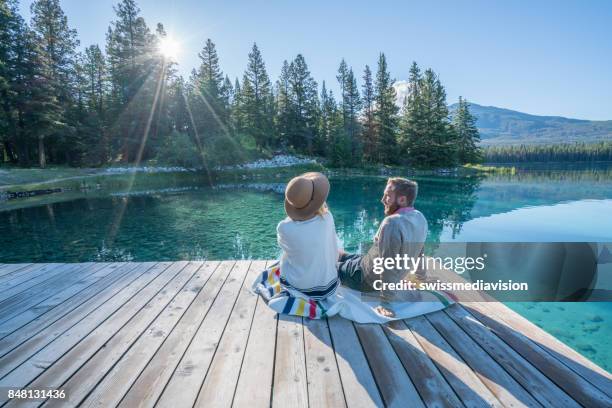 ungt par titta på soluppgången på sjön pier - idyllic lake bildbanksfoton och bilder