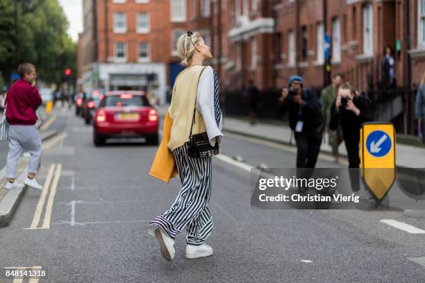 Caroline Daur wearing striped wide leg pants, Off White belt, knit, Prada bag outside JW Anderson during London Fashion Week September 2017 on...