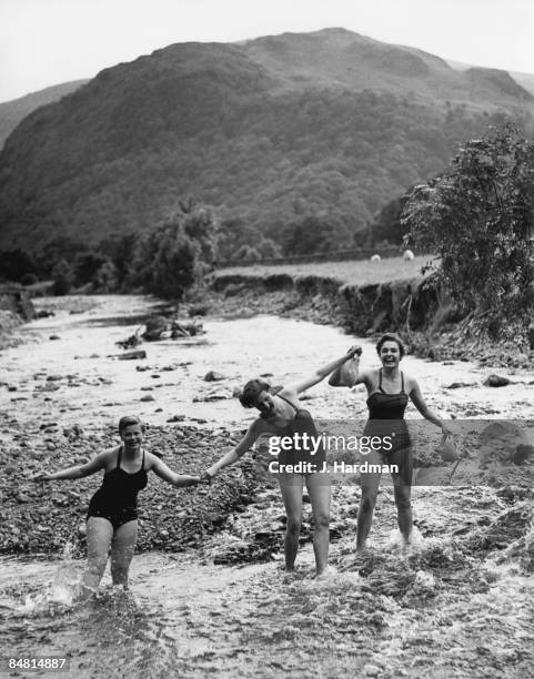 Holidaymakers Gillian Shrigley, Judith Dowling and Vicky Stahl paddling in the River Derwent near Borrowdale in the Lake District, Cumbria, after a...