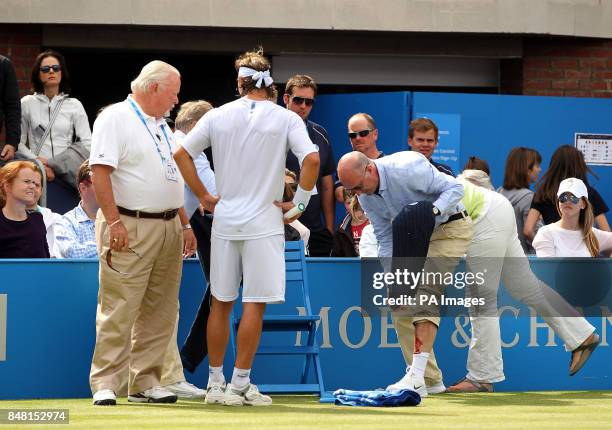 Line judge Andrew McDougall shows his injury caused after Argentina's David Nalbandian kicked an advertising board causing a cut to his leg during...