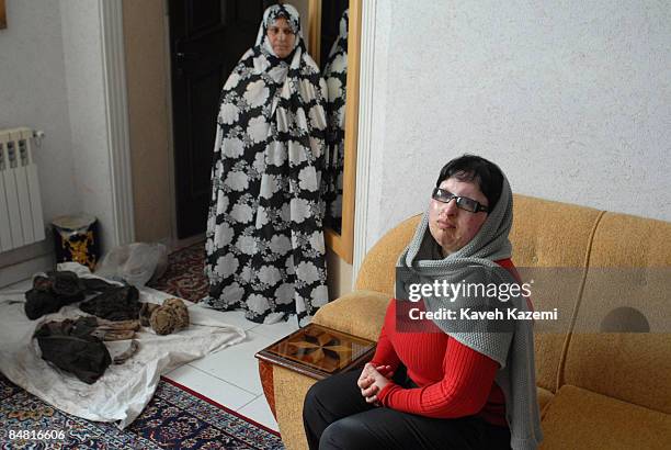 Ameneh Bahrami's mother stands in front of her clothing that was splashed by acid on the day of incident, while Ameneh sits on a sofa in their Tehran...