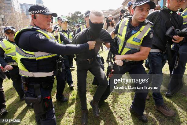 Masked protestor is detained by police as they enforce laws surrounding the wearing of masks to cover the face at rallies on September 17, 2017 in...