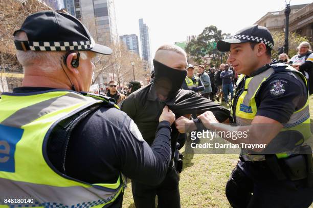 Masked protestor is detained by police as they enforce laws surrounding the wearing of masks to cover the face at rallies on September 17, 2017 in...