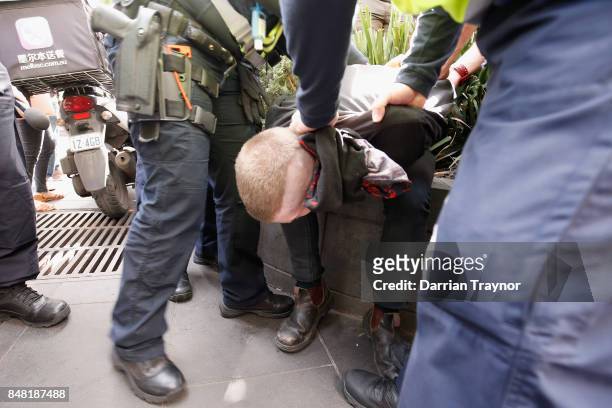 Masked protestor is detained by police as they enforce laws surrounding the wearing of masks to cover the face at rallies on September 17, 2017 in...
