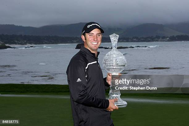Dustin Johnson poses with the trophy on th e18th green at Pebble Beach Golf Links after cancellation of the final round of the the AT&T Pebble Beach...