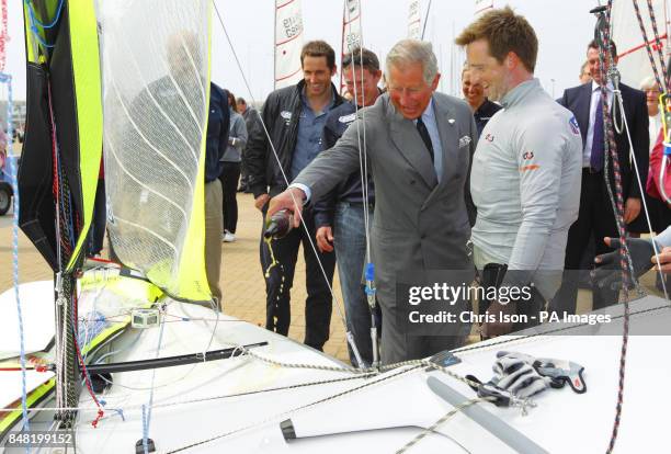 The Prince of Wales christens the British Olympic 49er boat of Stevie Morrison and Ben Rhodes with Dorset Gold beer as Ben Ainslie looks on during a...
