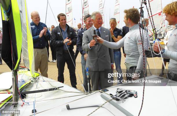 The Prince of Wales christens the British Olympic 49er boat of Stevie Morrison and Ben Rhodes with Dorset Gold beer as Ben Ainslie looks on during a...