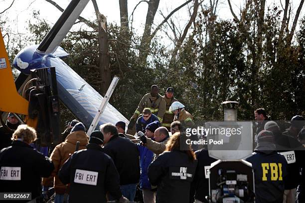 Workers and investigators clear debris from the scene of the plane crash of Continental Connection Flight 3407 on February 16, 2009 in Clarence, New...