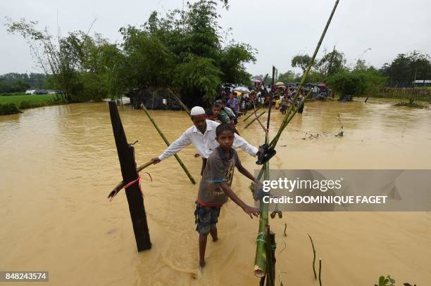 Rohingya refugees cross flood waters at Thangkhali refugee camp in Bangladesh's Cox's Bazar district on September 17, 2017. - Monsoon rain amid a...