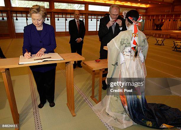 Secretary of State Hillary Clinton signs a book as U.S. Nuclear envoy Christopher Hill takes a sip of sake during a tour of the Meiji Shrine on...