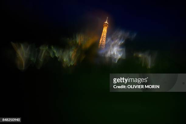 This photo taken on September 16, 2017 in Paris shows an illuminated Eiffel Tower as seen through droplets of water.