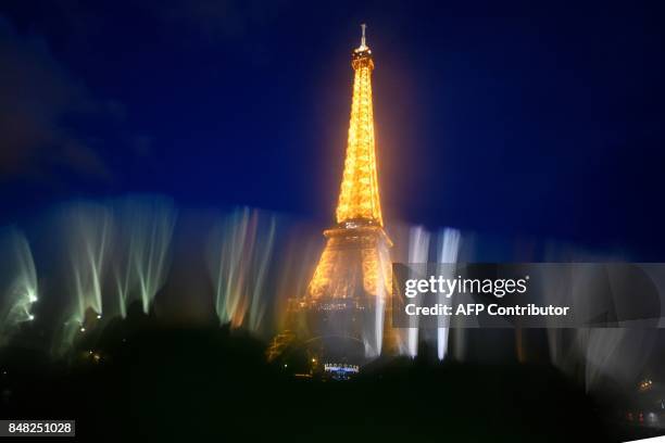 This photo taken on September 16, 2017 in Paris shows an illuminated Eiffel Tower as seen through droplets of water. / AFP PHOTO / Olivier MORIN