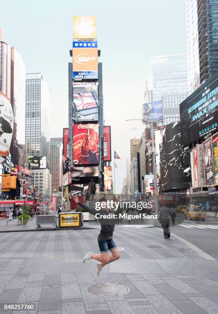 young woman jumping in air in times square - new york tourist stock-fotos und bilder
