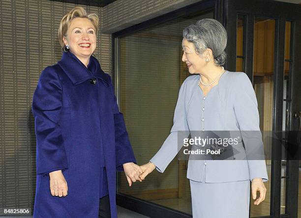 Secretary of State Hillary Rodham Clinton holds hands with Japan's Empress Michiko upon arriving to attend a tea party at Imperial Palace in Tokyo on...