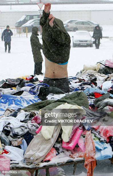 Man tries on garments at an open-air second-hand clothing and goods market outside Minsk in Zhdanovichi on February 17, 2009. The average monthly...