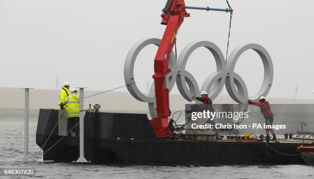 Engineers install a set of Olympic rings in the sea at the Weymouth and Portland Sailing Academy, Weymouth.