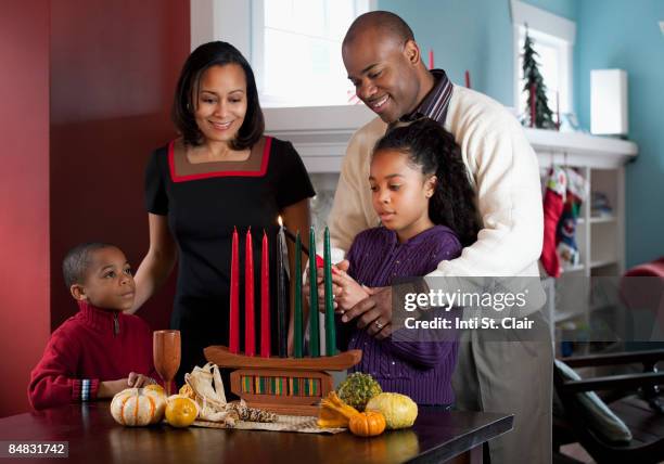 family lighting kinara for kwanzaa together - kwanzaa fotografías e imágenes de stock