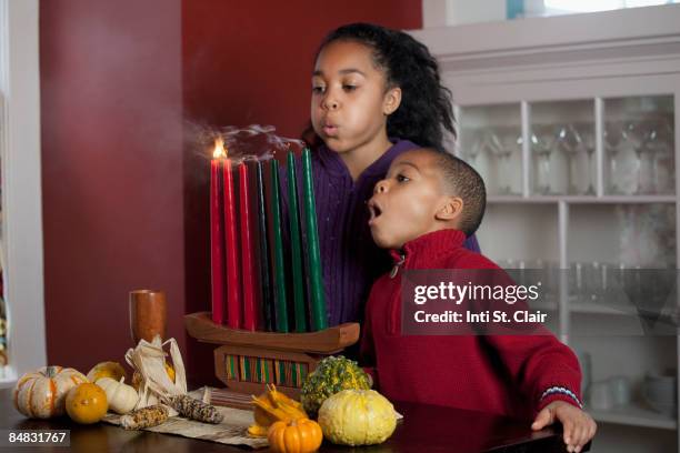 kids blowing out candles on kinara for kwanzaa - kwanzaa celebration stock pictures, royalty-free photos & images