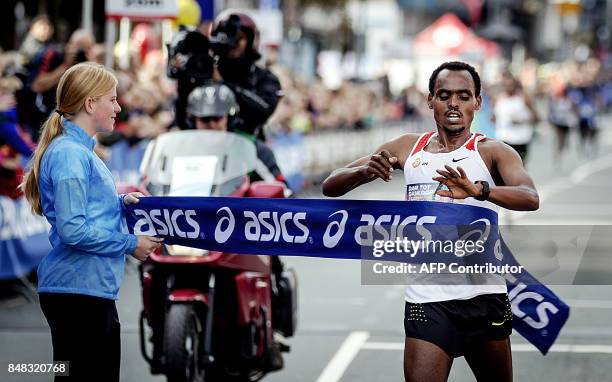 Ethiopa's Birhanu Legese chckes his watch as he crosses the line to win the men's event of the Dam tot Damloop, a 10-mile road running race from...