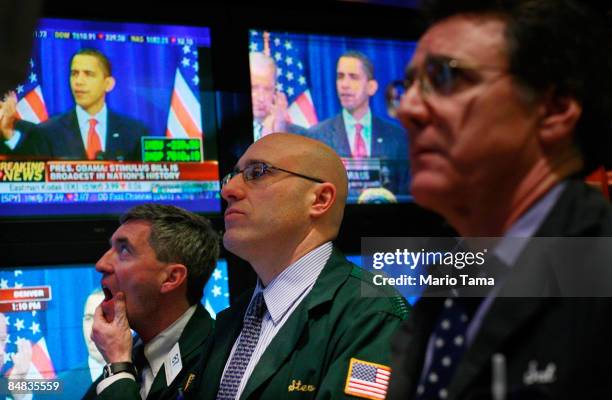 Traders work on the floor of the New York Stock Exchange during afternoon trading as President Barack Obama is seen on television at the economic...