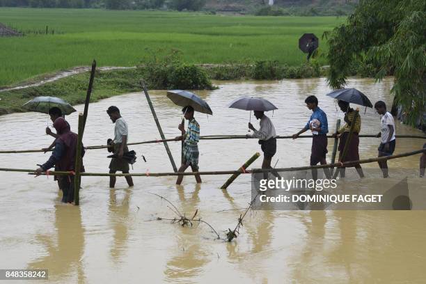 Rohingya Muslim refugees cross floodwater in Thyangkhali refugee camp near the Bangladesh town of Ukhia on September 17, 2017. Heavy monsoon rain...