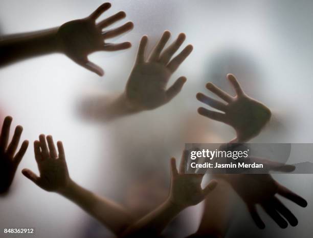 many hands silhouette behind glass - zombies stock-fotos und bilder