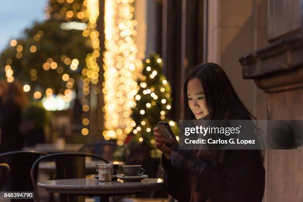girl smiles while texting family on her phone - outdoor christmas - christmas background no people stock pictures, royalty-free photos & images