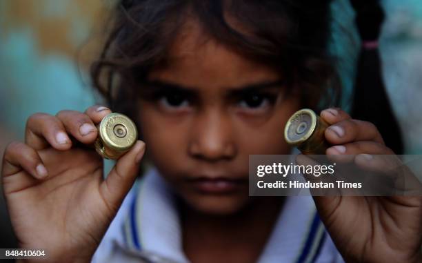 Child shows part of a mortar shell after a heavy mortar shelling by Pakistan Rangers on Saturday night, at Arnia village, on September 17, 2017 in...