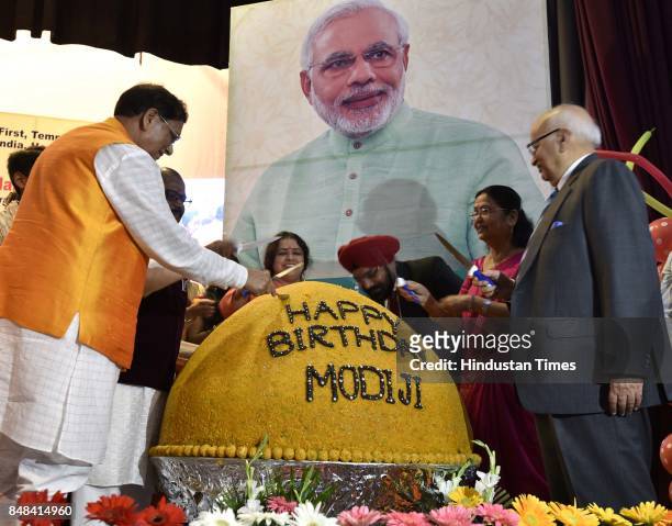 Bindeshwar Pathak, Founder, Sulabh International, and B.P. Singh with school children cutting a 567 Kg laddoo to celebrate the birthday of Prime...