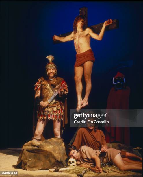 Photo of Motorhead in costume at a mock crucifixion scene in a studio in London in July 1984. Clockwise from top: Mick "Wurzel" Burston, Pete Gill,...