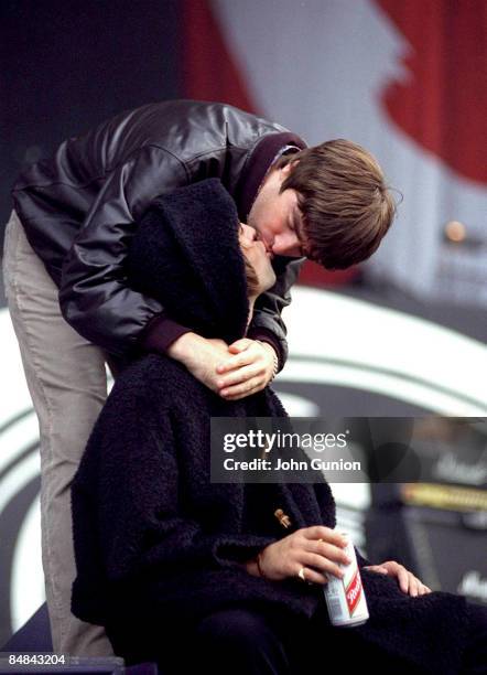 Photo of OASIS and Liam GALLAGHER and Noel GALLAGHER; Noel Gallagher & Liam Gallagher, kissing, on stage at Glasgow Green Festival