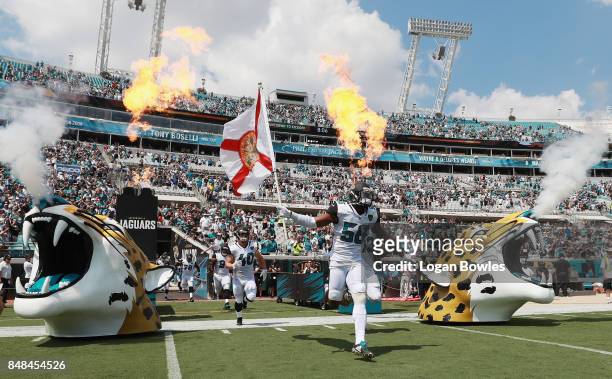 Dante Fowler of the Jacksonville Jaguars takes the field with his teammates and a Florida state flag prior to the start of their game against the...